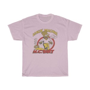 May include: A pink t-shirt featuring a cartoon image of Bart Simpson as a rapper. The image is in a circle with the text "Dancin' Machine" above and "M.C. Bart" below. The text inside the circle says "You can't touch this!"