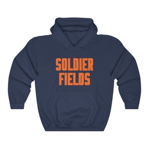 Könnte beinhalten: Ein marineblauer Kapuzenpullover mit dem Aufdruck "SOLDIER FIELDS" in Orange auf der Vorderseite.