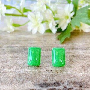 May include: A pair of green jade stone earrings. The earrings are rectangular in shape and have a smooth, polished finish.