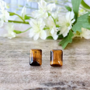 May include: A pair of gold stud earrings with rectangular tiger's eye stones.