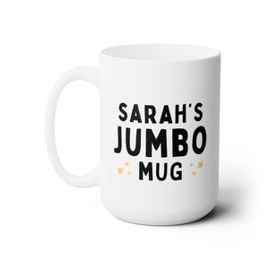Może przedstawiać: Biały kubek jumbo z ceramiki z czarnym tekstem, kt&oacute;ry brzmi "SARAH'S JUMBO MUG" z dwiema złotymi gwiazdkami po obu stronach słowa "MUG".