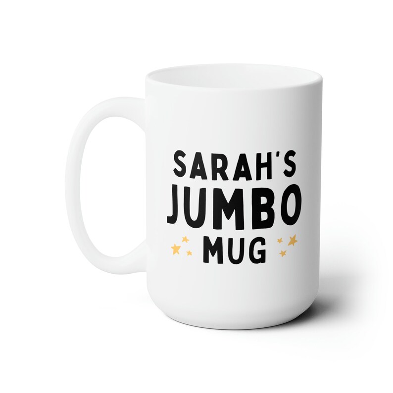 Może przedstawiać: Biały kubek jumbo z ceramiki z czarnym tekstem, kt&oacute;ry brzmi "SARAH'S JUMBO MUG" z dwiema złotymi gwiazdkami po obu stronach słowa "MUG".