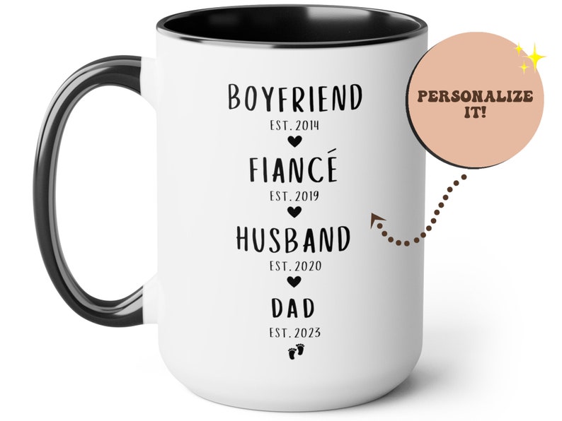 K&ouml;nnte beinhalten: Wei&szlig;e Keramik-Kaffeetasse mit schwarzem Henkel und schwarzem Rand. Die Tasse hat schwarzen Text, der "Boyfriend Est. 2014", "Fianc&eacute; Est. 2019", "Husband Est. 2020" und "Dad Est. 2023" lautet.