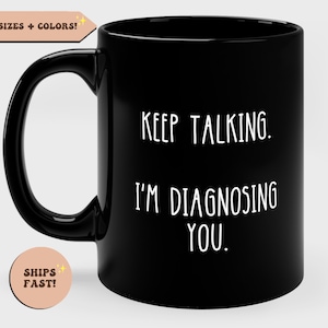 May include: Black coffee mug with white text that reads "KEEP TALKING. I'M DIAGNOSING YOU."