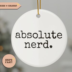 May include: White ceramic ornament with black text that reads "absolute nerd."