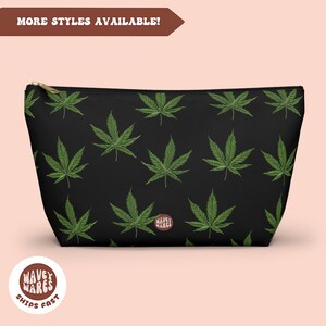 May include: Black zippered pouch with a repeating pattern of green marijuana leaves. The pouch has a gold zipper and the text "Wavey Wares" is printed on the bottom of the pouch.
