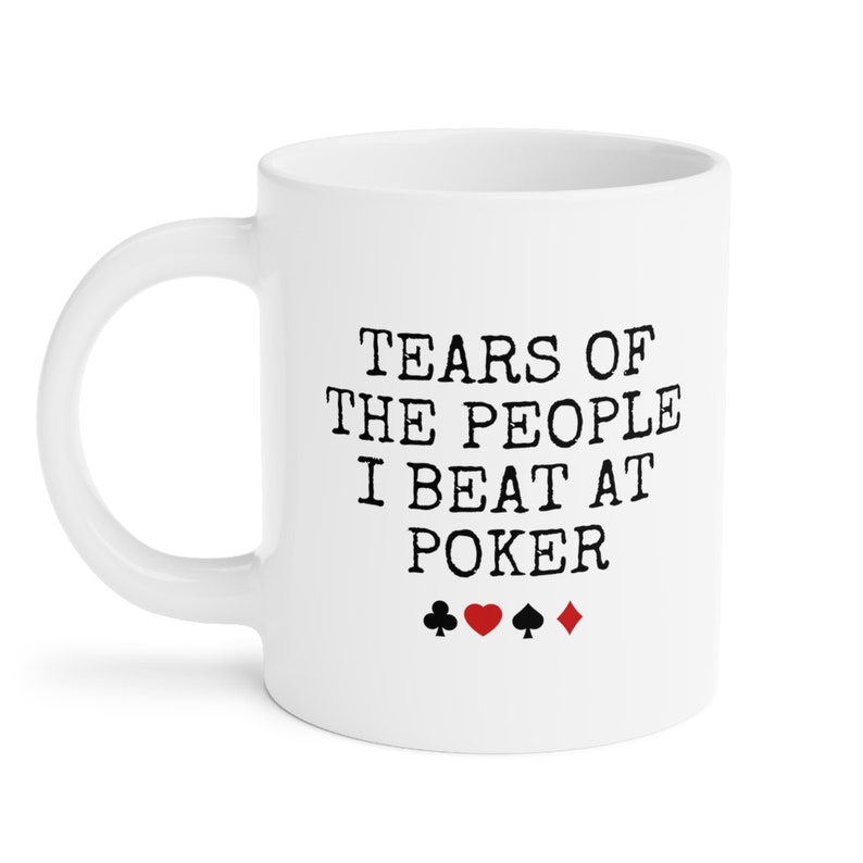 Puede incluir: Taza de caf&eacute; de cer&aacute;mica blanca con texto negro que dice "Tears of the people I beat at poker" y cuatro s&iacute;mbolos de palo de cartas negras: una pica, un coraz&oacute;n, un tr&eacute;bol y un diamante.