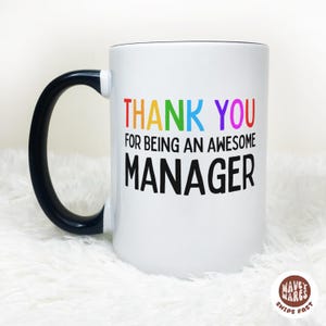 Può includere: Tazza in ceramica bianca con manico e bordo neri. La tazza presenta la scritta "THANK YOU FOR BEING AN AWESOME MANAGER" in lettere colorate. Un regalo per un manager.