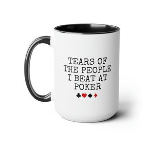 Puede incluir: Taza de caf&eacute; de cer&aacute;mica blanca con borde y asa negros. La taza tiene texto negro que dice "Tears of the people I beat at poker" con cuatro s&iacute;mbolos de palos de cartas debajo del texto.