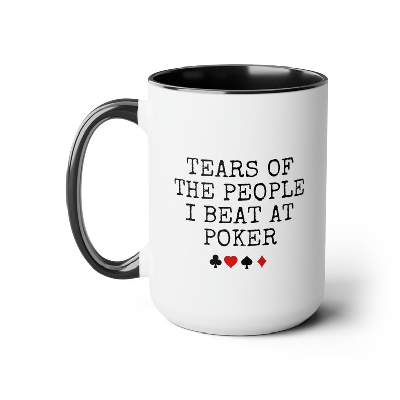 Puede incluir: Taza de caf&eacute; de cer&aacute;mica blanca con borde y asa negros. La taza tiene texto negro que dice "Tears of the people I beat at poker" con cuatro s&iacute;mbolos de palos de cartas debajo del texto.