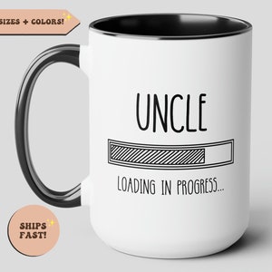 May include: White ceramic coffee mug with a black rim and handle. The mug has black text that reads "UNCLE" and a progress bar with the text "LOADING IN PROGRESS..."