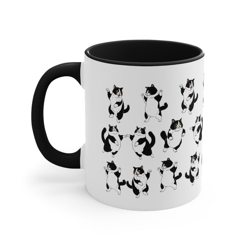 May include: White ceramic mug with a black handle and interior. The mug features a repeating pattern of cartoon tuxedo cats in various poses. The cats are black and white, with some having one yellow eye.