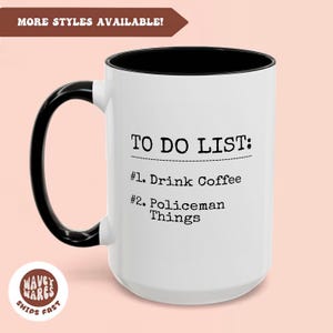 May include: White ceramic coffee mug with a black rim and handle. The mug has black text that reads "TO DO LIST: #1. Drink Coffee #2. Policeman Things".
