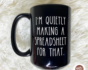 May include: Black ceramic mug with a large handle. The mug features the white text, "I'M QUIETLY MAKING A SPREADSHEET FOR THAT." A small, round logo with the words "WAVEY WARES" and "SHIPS FAST" is on the bottom right.