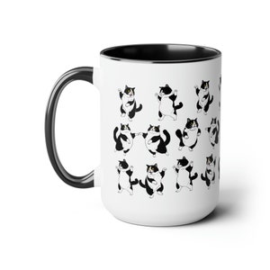 May include: White ceramic mug with a black interior and handle. The mug is decorated with a repeating pattern of black and white cartoon cats in various poses. The cats have black and white markings.