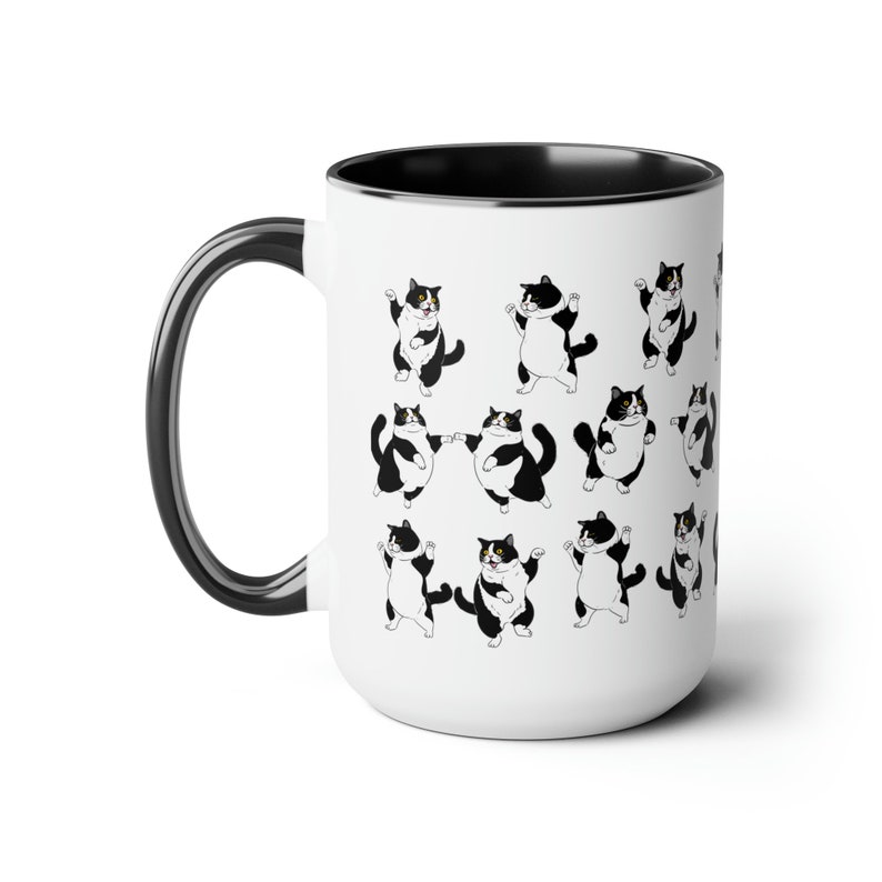 May include: White ceramic mug with a black interior and handle. The mug is decorated with a repeating pattern of black and white cartoon cats in various poses. The cats have black and white markings.