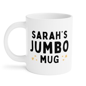 Może przedstawiać: Biały kubek ceramiczny z czarnym tekstem, kt&oacute;ry brzmi "SARAH'S JUMBO MUG" z trzema złotymi gwiazdkami po obu stronach tekstu.