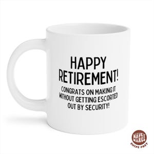 K&ouml;nnte beinhalten: Wei&szlig;e Keramik-Tasse mit dem schwarzen Text "HAPPY RETIREMENT!". Die Tasse enth&auml;lt auch die Botschaft "CONGRATS ON MAKING IT WITHOUT GETTING ESCORTED OUT BY SECURITY!". Ein Geschenk zum Thema Ruhestand.