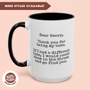 Könnte beinhalten: Eine weiße Keramiktasse mit schwarzem Henkel und schwarzem Rand. Die Tasse hat ein schwarz-weißes Textdesign mit der Aufschrift "Lieber Henry, Danke, dass du mein Chef bist. Wenn ich einen anderen Chef hätte, würde ich ihm in die Kehle schlagen und dich suchen gehen."