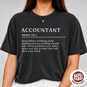 Può includere: Una t-shirt a maniche corte grigio antracite con testo bianco che recita ACCOUNTANT noun (n.) Spreadsheet wielding multi-tasking miracle working wizard who solves problems you didn't know you had in ways that will blow your mind.
