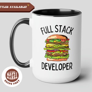 Puede incluir: Taza de cerámica blanca con borde y asa negros. La taza tiene una ilustración en blanco y negro de una hamburguesa grande con el texto "Full Stack Developer" impreso en ella.