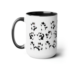 May include: White ceramic mug with a black interior and handle. The mug is decorated with a repeating pattern of black and white cartoon cats in various poses. The cats have a tuxedo pattern.