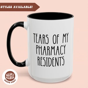 May include: White ceramic coffee mug with a black handle and rim. The mug has black text that reads "Tears of my Pharmacy Residents".