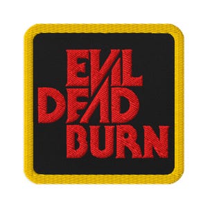 May include: Embroidered patch with the words "EVIL DEAD BURN" in red, stylized lettering on a black background. The patch has a yellow border. The design is likely for a horror movie or fan merchandise.