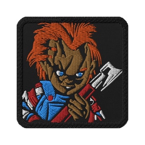 Könnte beinhalten: Gestickter Aufnäher mit einer Comicfigur mit roten Haaren, einem blau-rot gestreiften Hemd und einer weißen Axt. Die Figur hat ein verschmitztes Grinsen und hält die Axt in ihrer rechten Hand.