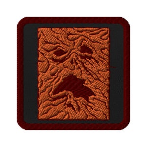 Könnte beinhalten: Ein quadratischer gestickter Aufnäher mit rotem Rand und schwarzem Hintergrund. Der Aufnäher zeigt ein detailliertes orangefarbenes und braunes gesticktes Bild eines gruseligen Gesichts.