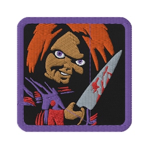 Può includere: Toppa ricamata con una bambola dai capelli rossi che tiene un coltello insanguinato. La bambola ha gli occhi viola e un sorriso sinistro. La toppa è su uno sfondo nero con un bordo viola.