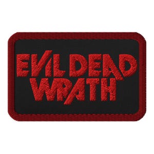 May include: Embroidered patch with the words "EVIL DEAD WRATH" in red, stylized lettering on a black background. The patch has a rectangular shape with a red border. The design is likely for fans of horror films.