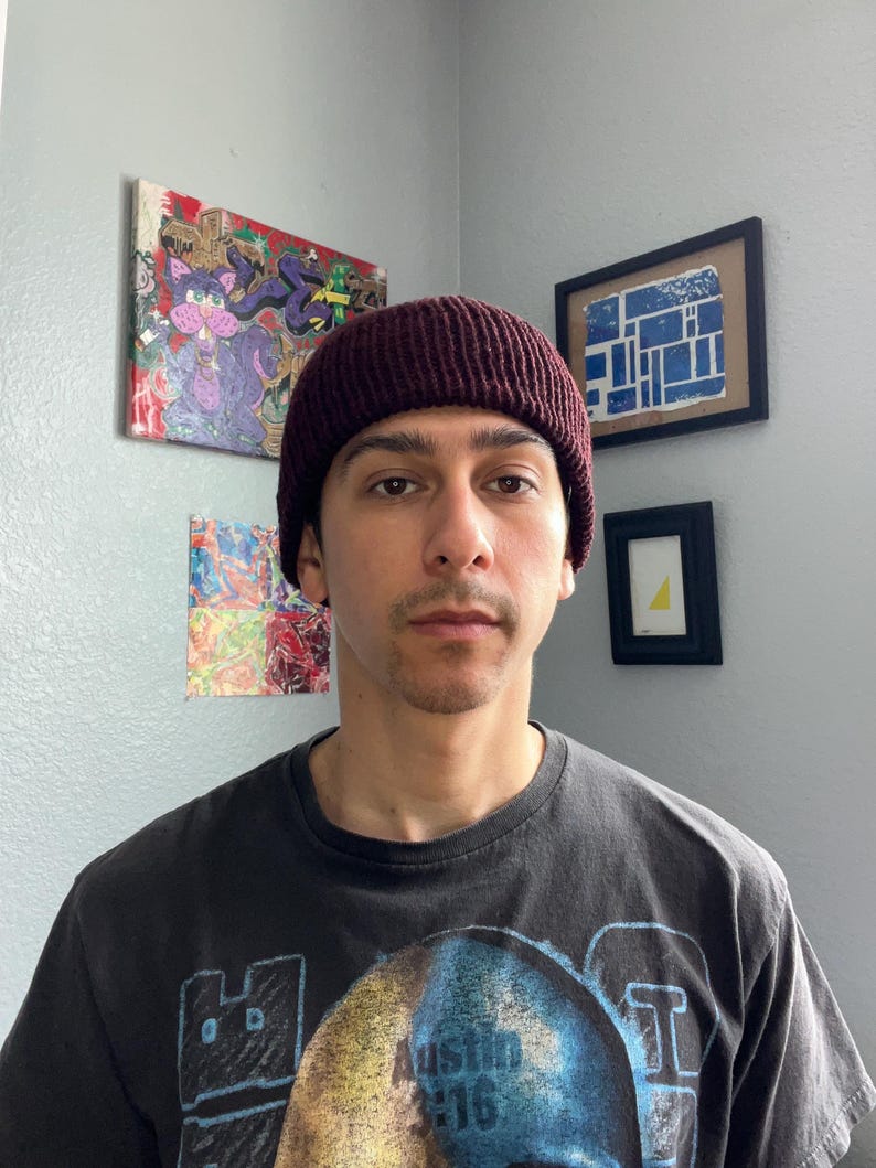 Puede incluir: Un gorro de punto color granate oscuro con textura acanalada. El gorro se lleva puesto en la cabeza y presenta un dise&ntilde;o de borde grueso y doblado que se ajusta c&oacute;modamente sobre las orejas. El tejido tiene un patr&oacute;n de canal&eacute; vertical.