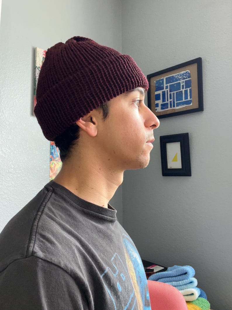 Puede incluir: Un gorro de punto color burdeos oscuro con un borde grueso doblado. El gorro presenta una textura acanalada vertical prominente en toda la superficie, lo que proporciona un ajuste ce&ntilde;ido alrededor de la cabeza. El material es de lana.