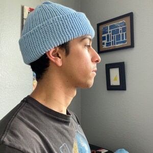 Puede incluir: Un gorro de punto de color azul claro con un borde grueso doblado. El gorro presenta una textura acanalada en toda su superficie, confeccionado con hilo en un tono azul p&aacute;lido s&oacute;lido. El dise&ntilde;o es sencillo, funcional y cubre la cabeza.