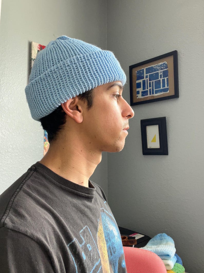 Puede incluir: Un gorro de punto de color azul claro con un borde grueso doblado. El gorro presenta una textura acanalada en toda su superficie, confeccionado con hilo en un tono azul p&aacute;lido s&oacute;lido. El dise&ntilde;o es sencillo, funcional y cubre la cabeza.