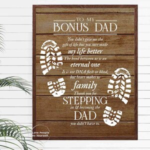 Puede incluir: Un letrero de madera marr&oacute;n con texto blanco que dice "To My Bonus Dad". El letrero tiene un dise&ntilde;o de huella blanca y el texto "You didn't give me the gift of life but you sure made my life better. The bond between us is an eternal one. It is not DNA flesh or blood, but heart makes us family. Thank you for stepping in & becoming the Dad you didn't have to."