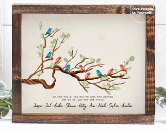 May include: A framed print featuring a watercolour illustration of a tree branch with colourful birds. The text reads "To the world you may be just one person but to us you are the world" and lists names: Jasper, Joel, Amber, Shawn, Katy, Ava, Noah, Sophia, Amalia. The bottom right corner of the frame has the text "Love People As Yourself."