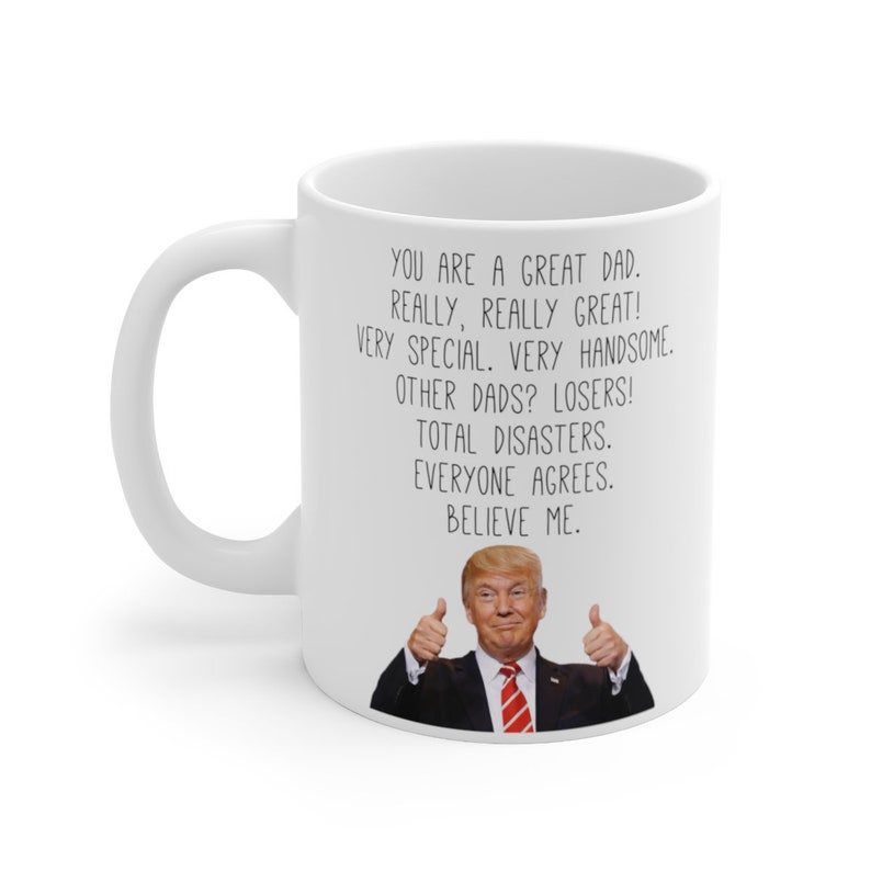 May include: White ceramic mug with a black and white image of a man with a thumbs up gesture. The text on the mug reads "You are a great dad. Really, really great! Very special. Very handsome. Other dads? Losers! Total disasters. Everyone agrees. Believe me."