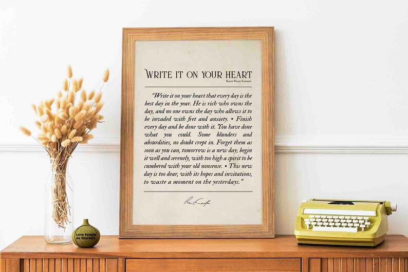 May include: A framed print with a beige background and a black text quote by Ralph Waldo Emerson that reads "Write it on your heart that every day is the best day in the year. He is rich who owns the day, and no one owns the day who allows it to be invaded with fret and anxiety. Finish every day and be done with it. You have done what you could. Some blunders and absurdities, no doubt crept in. Forget them as soon as you can, tomorrow is a new day; begin it well and serenely, with too high a spirit to be cumbered with your old nonsense. This new day is too dear, with its hopes and invitations, to waste a moment on the yesterdays."