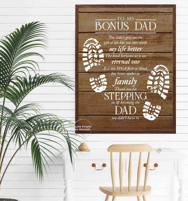Puede incluir: Un letrero de madera marr&oacute;n con texto blanco que dice "To My Bonus Dad". El letrero tiene un dise&ntilde;o de huella blanca y el texto "You didn't give me the gift of life but you sure made my life better. The bond between us is an eternal one. It is not DNA flesh or blood, but heart makes us family. Thank you for stepping in & becoming the Dad you didn't have to."