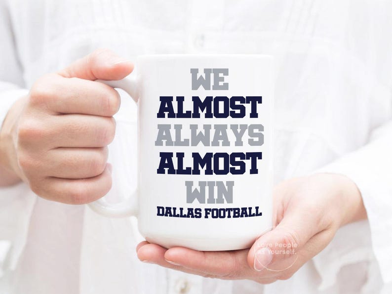 May include: White ceramic mug with the text "We almost always almost win Dallas Football" in navy blue and gray lettering.