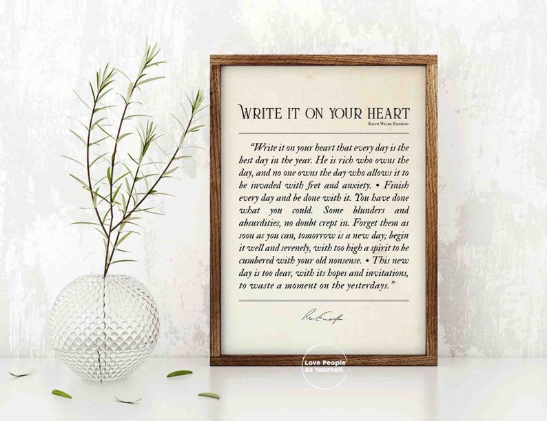 May include: A framed print with a white background and black text. The text is a quote by Ralph Waldo Emerson that reads "Write it on your heart that every day is the best day in the year. He is rich who owns the day, and no one owns the day who allows it to be invaded with fret and anxiety. Finish every day and be done with it. You have done what you could. Some blunders and absurdities, no doubt crept in. Forget them as soon as you can, tomorrow is a new day; begin it well and serenely, with too high a spirit to be cumbered with your old nonsense. This new day is too dear, with its hopes and invitations, to waste a moment on the yesterdays." The quote is attributed to Ralph Waldo Emerson. The print also includes the text "Love People As Yourself."