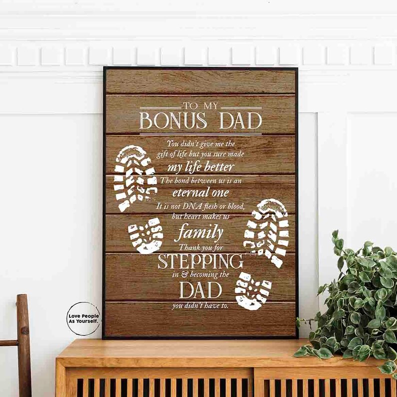 Puede incluir: Un fondo de madera con texto blanco que dice "To My Bonus Dad." El texto contin&uacute;a con un mensaje sobre el v&iacute;nculo entre un padrastro y un hijo. El fondo est&aacute; decorado con huellas blancas.