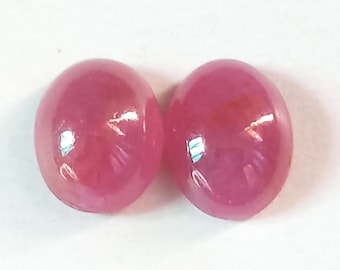 May include: Two round, pink ruby gemstones. The gemstones are smooth and have a high gloss finish.