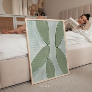 May include: A framed abstract painting with a light blue background and green leaf shapes. The painting is titled "By Gabis".
