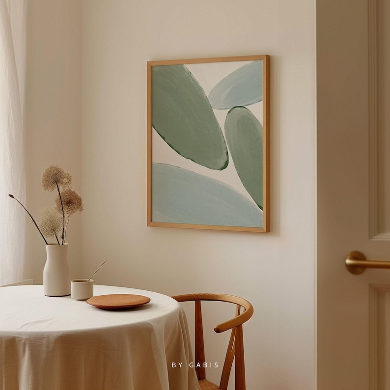 May include: A framed abstract painting with a light blue and green colour scheme. The painting features overlapping organic shapes and is displayed on a white wall.