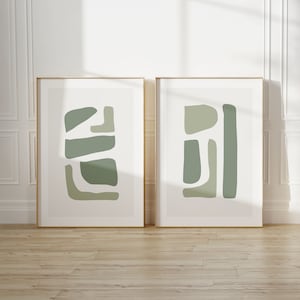 May include: Two framed abstract art prints with a minimalist design. The prints feature geometric shapes in shades of green on a white background.
