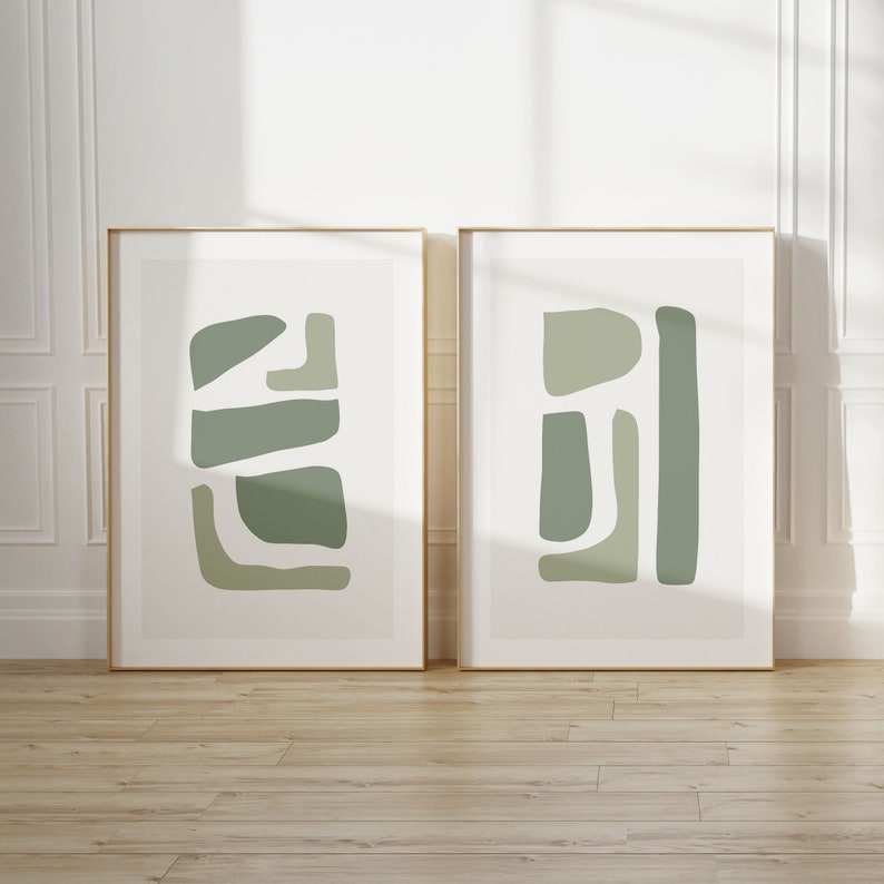 May include: Two framed abstract art prints with a minimalist design. The prints feature geometric shapes in shades of green on a white background.