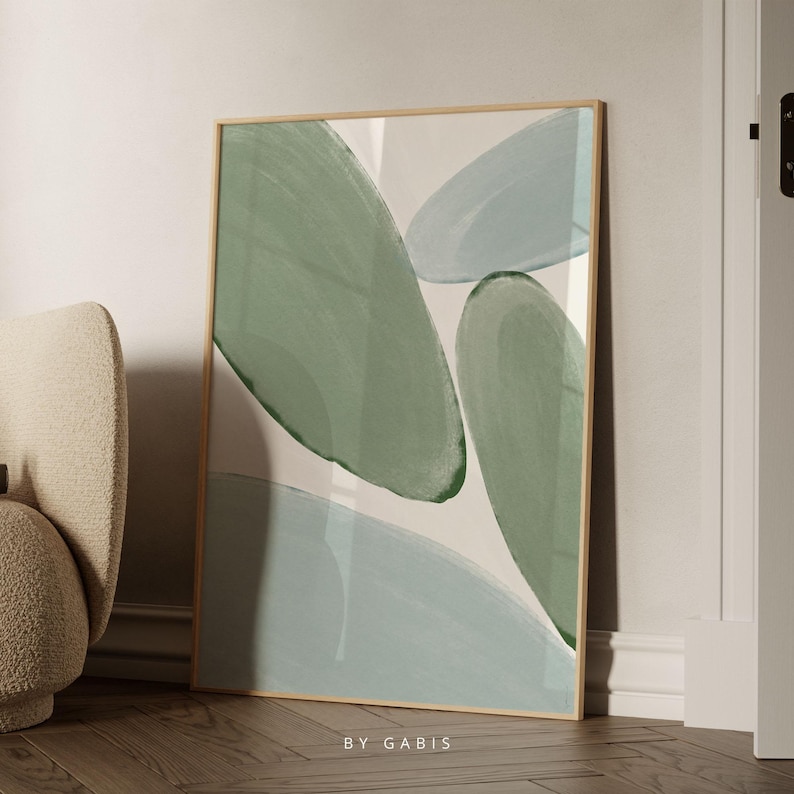May include: Abstract art print featuring green and blue shapes on a white background. The print is framed in a light wood frame and bears the text "BY GABIS" at the bottom.
